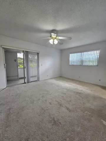 an empty room with a chandelier fan and windows