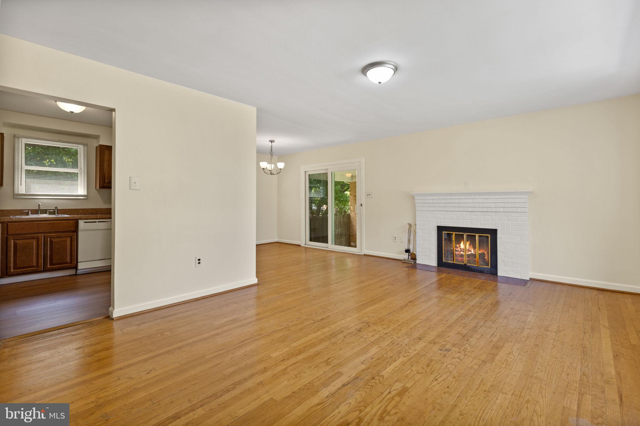 a view of an empty room with wooden floor and a fireplace