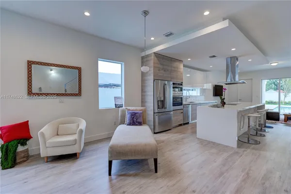 a living room with furniture kitchen view and a flat screen tv
