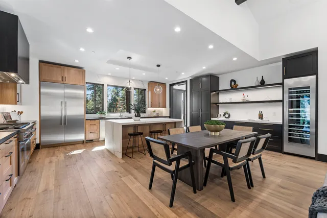 a kitchen with stainless steel appliances kitchen island granite countertop a dining table chairs refrigerator and sink