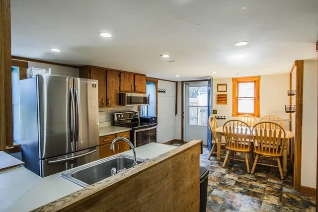 a kitchen with granite countertop a refrigerator and chairs