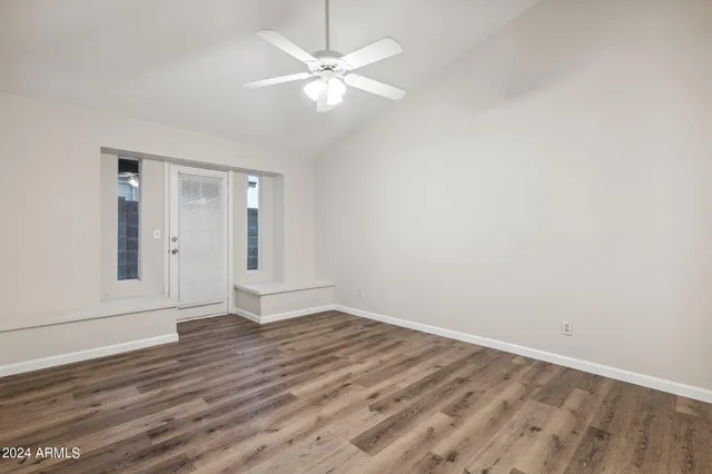an empty room with wooden floor and fan