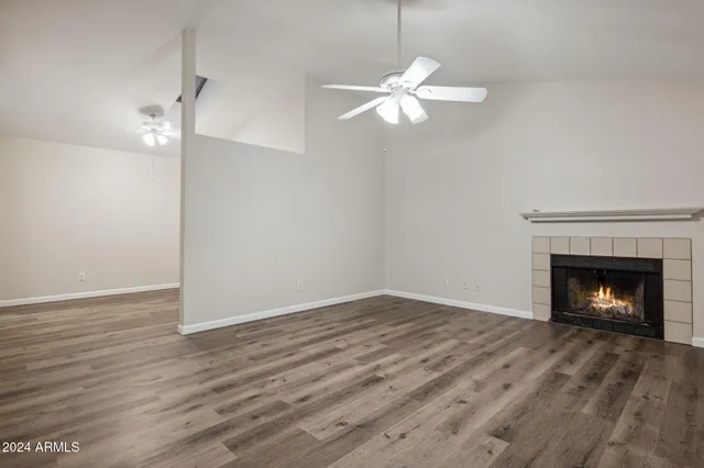 a view of an empty room with wooden floor fireplace and a window