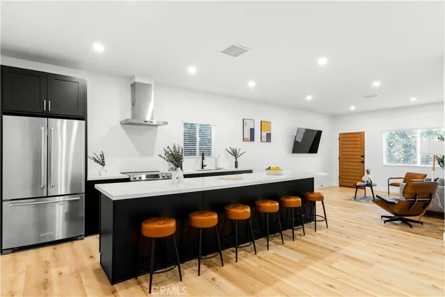 a kitchen with stainless steel appliances granite countertop a refrigerator a sink dishwasher a stove and a dining table with wooden floor