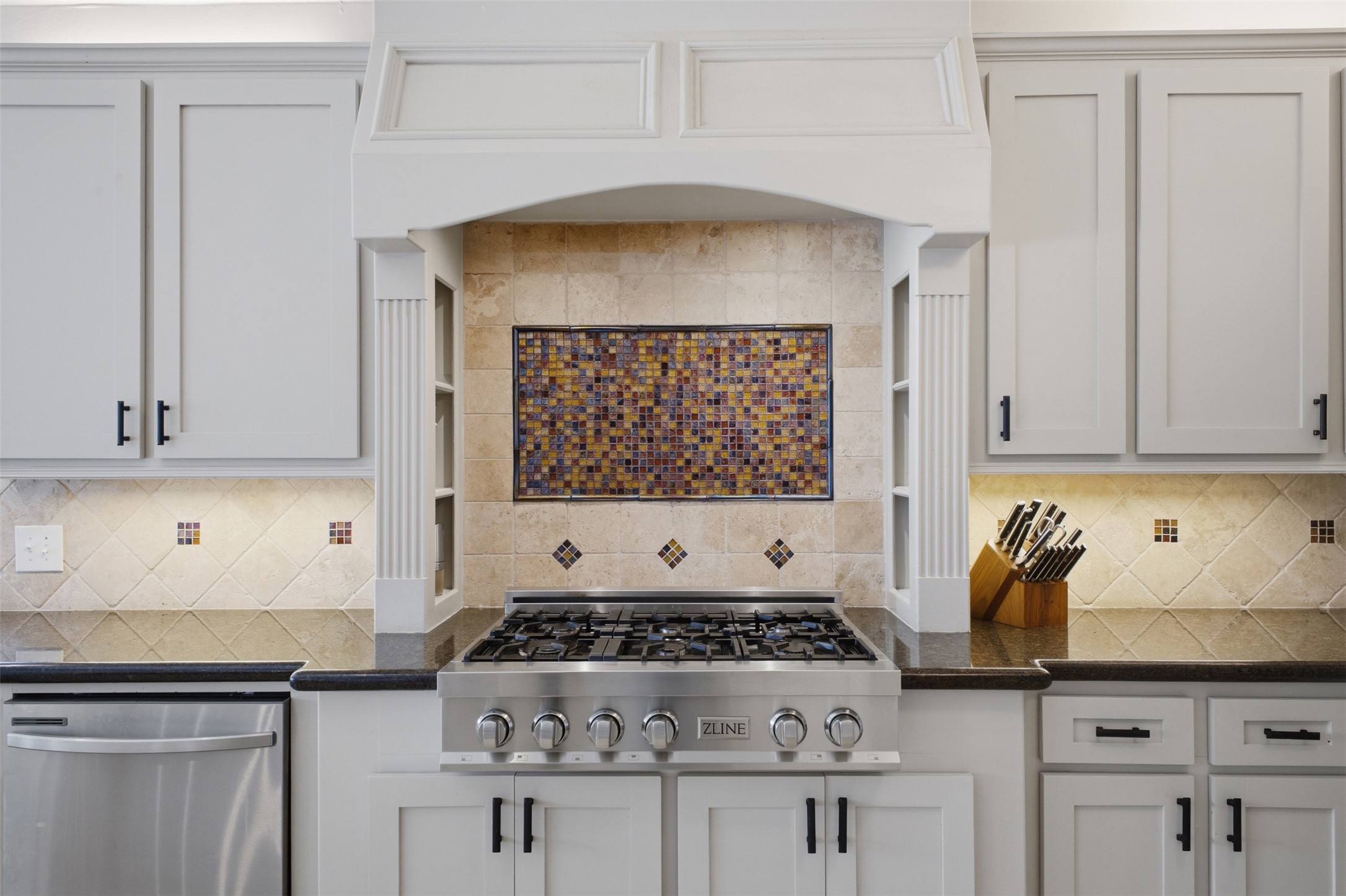 12710 Aries Loop Willis, TX 77318 - Photo 15 of 40 The kitchen features light-colored cabinetry, dark countertops, a stainless steel gas range, and a tiled backsplash with decorative accents