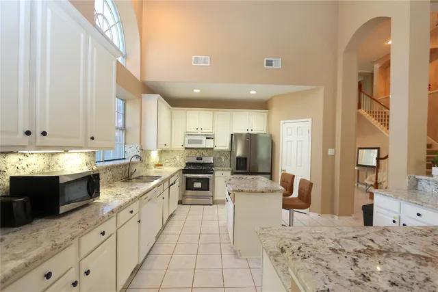 a large kitchen with stainless steel appliances kitchen island granite countertop a sink and cabinets