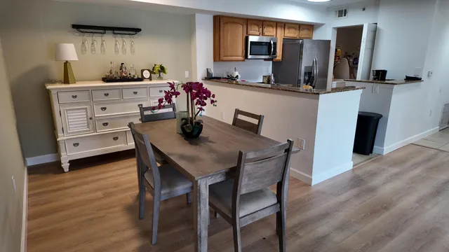 a kitchen with stainless steel appliances a dining table chairs refrigerator and sink