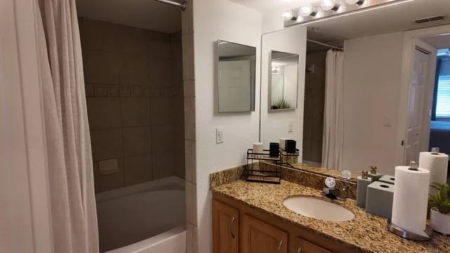 a bathroom with a granite countertop sink mirror and shower