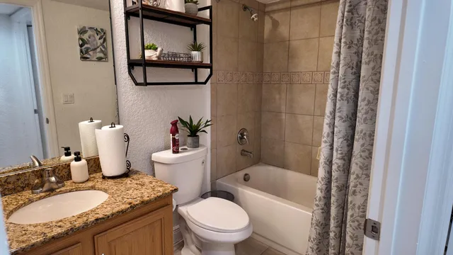 a bathroom with a granite countertop toilet sink and mirror