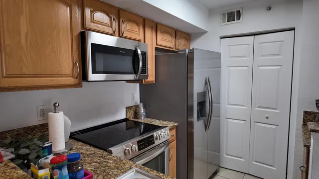 a kitchen with stainless steel appliances granite countertop a refrigerator and a stove top oven