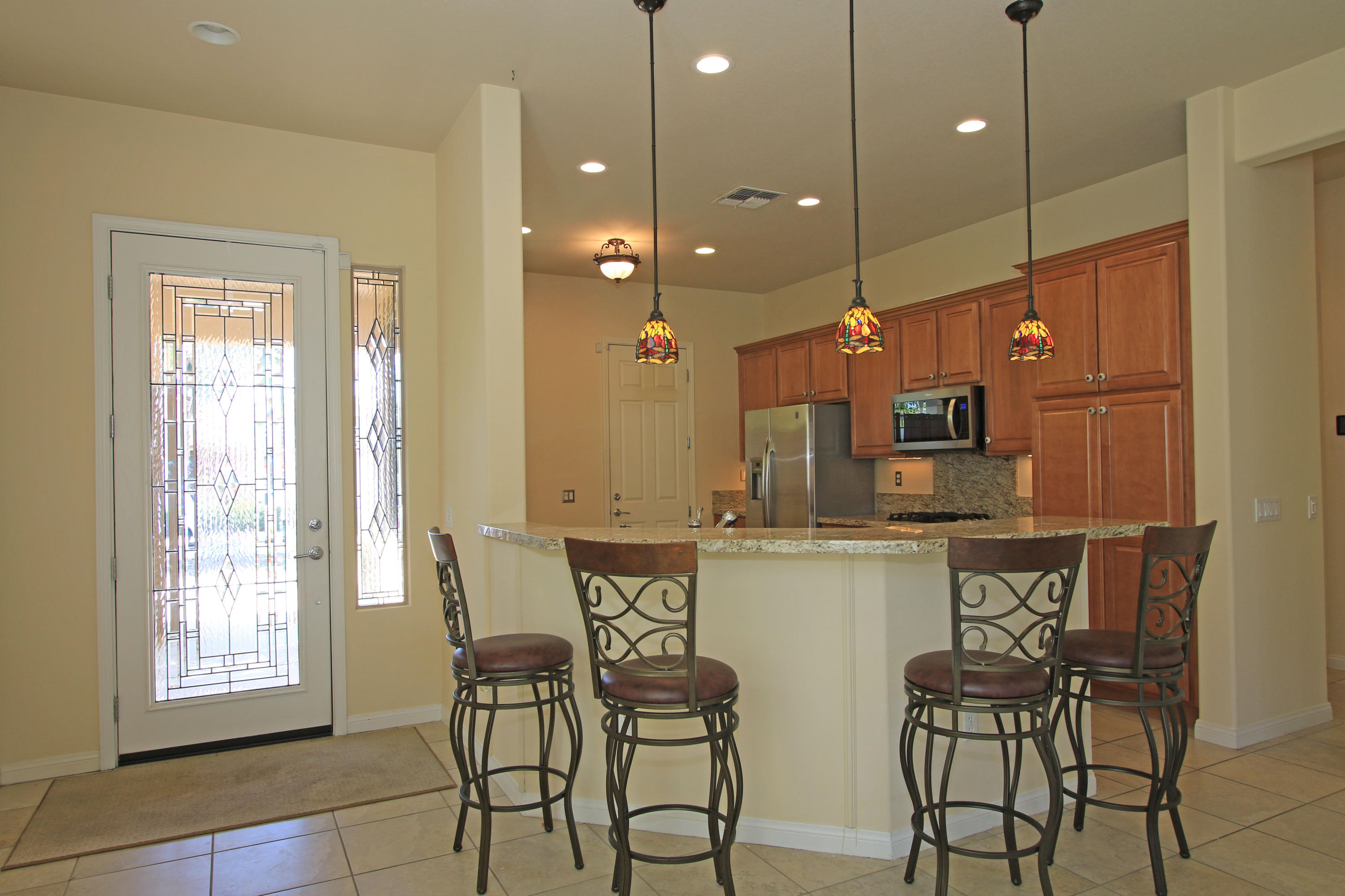 81642 Avenida Bolero Indio, CA 92203 - Photo 6 of 38 a kitchen with stainless steel appliances a dining table chairs and white cabinets