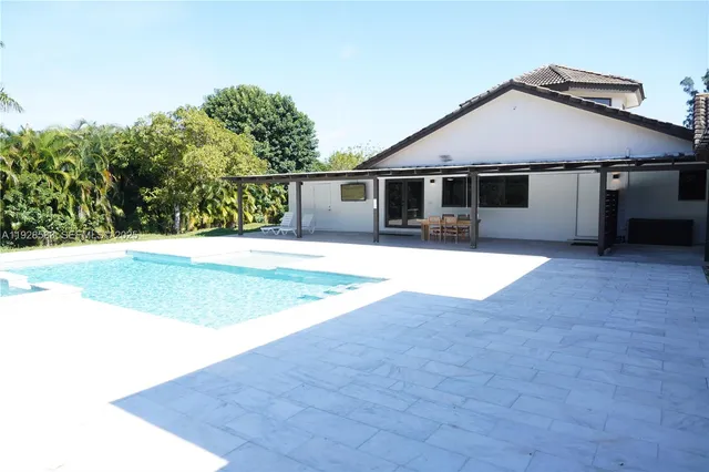 a view of a patio with table and chairs under an umbrella with a big yard
