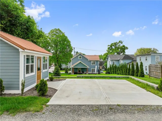 a view of white house with a yard and table and chairs under an umbrella