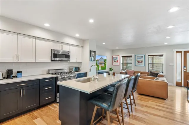 a kitchen with stainless steel appliances granite countertop a stove top oven a sink dishwasher a dining table and chairs with wooden floor