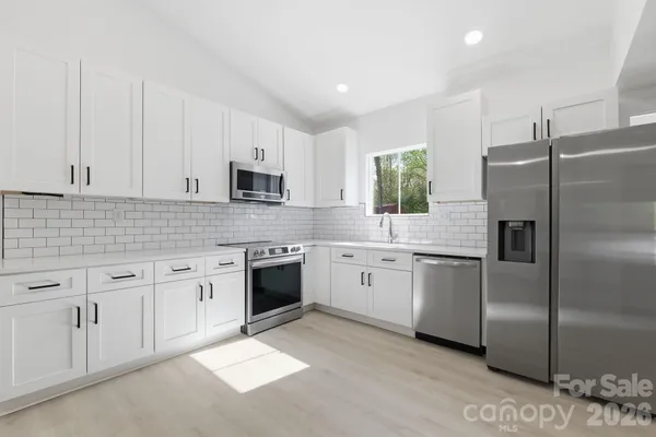 a kitchen with granite countertop a refrigerator sink and stove