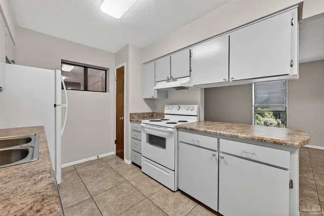 a kitchen with granite countertop white cabinets and white appliances