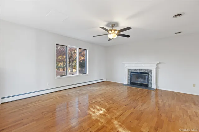 a view of an empty room with a window and wooden floor