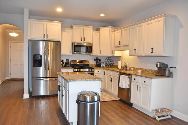 a kitchen with stainless steel appliances granite countertop a refrigerator a stove top oven a sink and cabinets