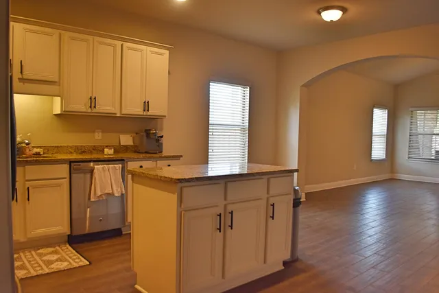 a kitchen with stainless steel appliances granite countertop a stove a sink and a refrigerator with wooden floors