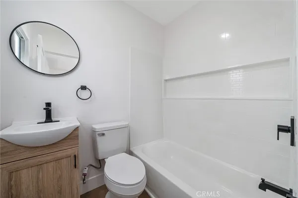 a bathroom with a toilet a sink a mirror and bathtub