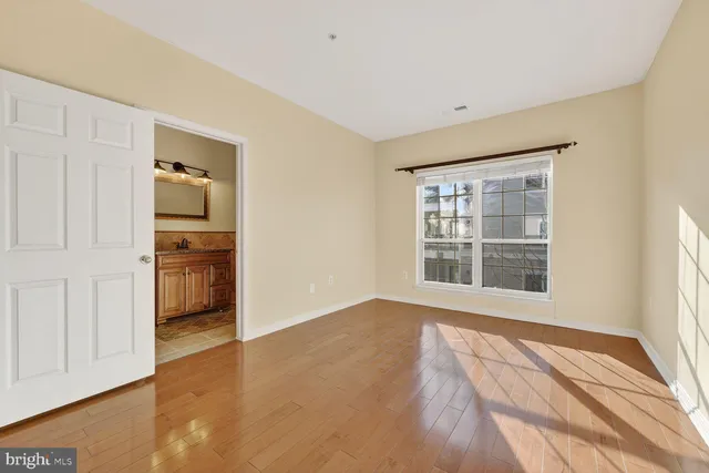 a view of empty room with wooden floor and windows