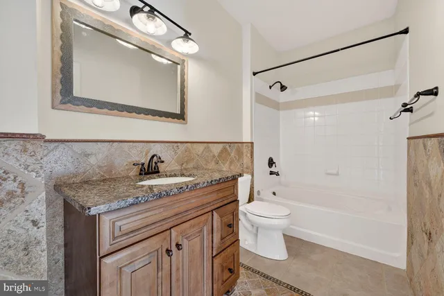 a bathroom with a granite countertop sink a toilet and a mirror
