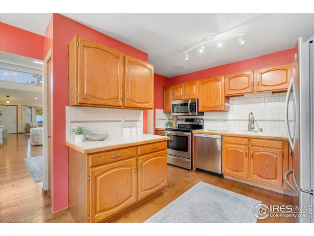 a kitchen with stainless steel appliances granite countertop a stove a sink dishwasher and a refrigerator with wooden cabinets