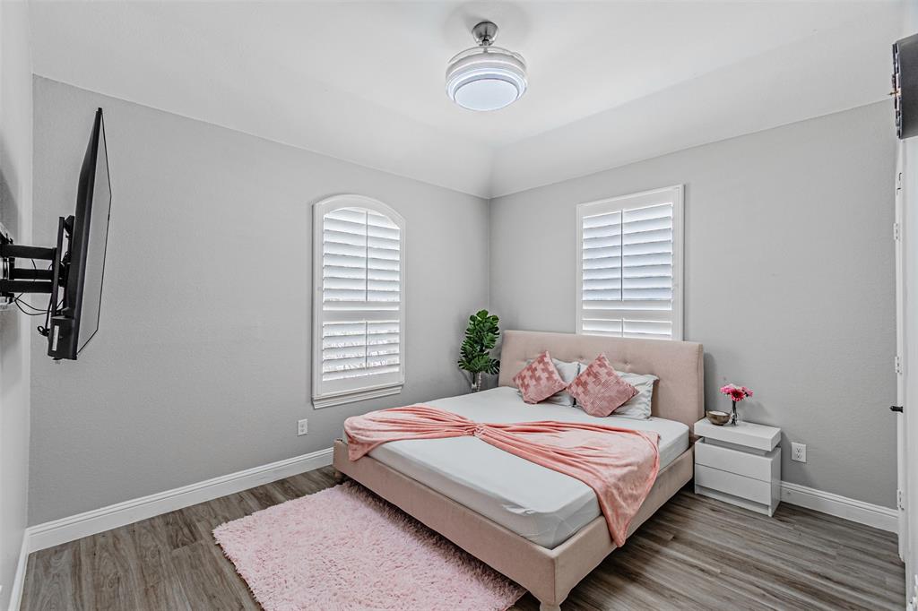 1805 Stetson Way Allen, TX 75002 - Photo 15 of 22 Bedroom featuring wood-finish flooring, two arched windows with plantation shutters, and a mounted ceiling light fixture