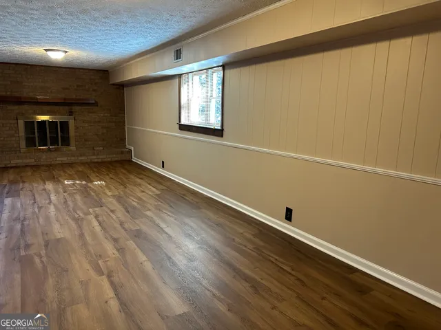 an empty room with wooden floor closet and windows