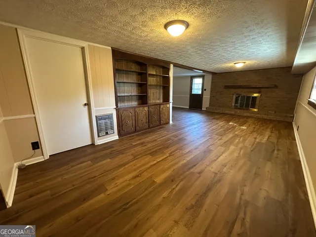 a view of empty room with wooden floor and fireplace