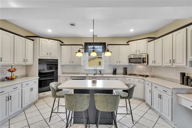 a kitchen with granite countertop a center island a counter space stainless steel appliances cabinets and a counter top space