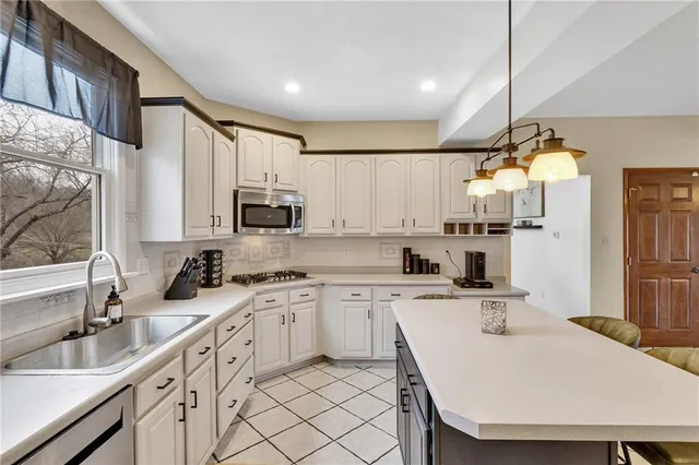 a kitchen with stainless steel appliances a sink a stove a refrigerator cabinets and a counter top space