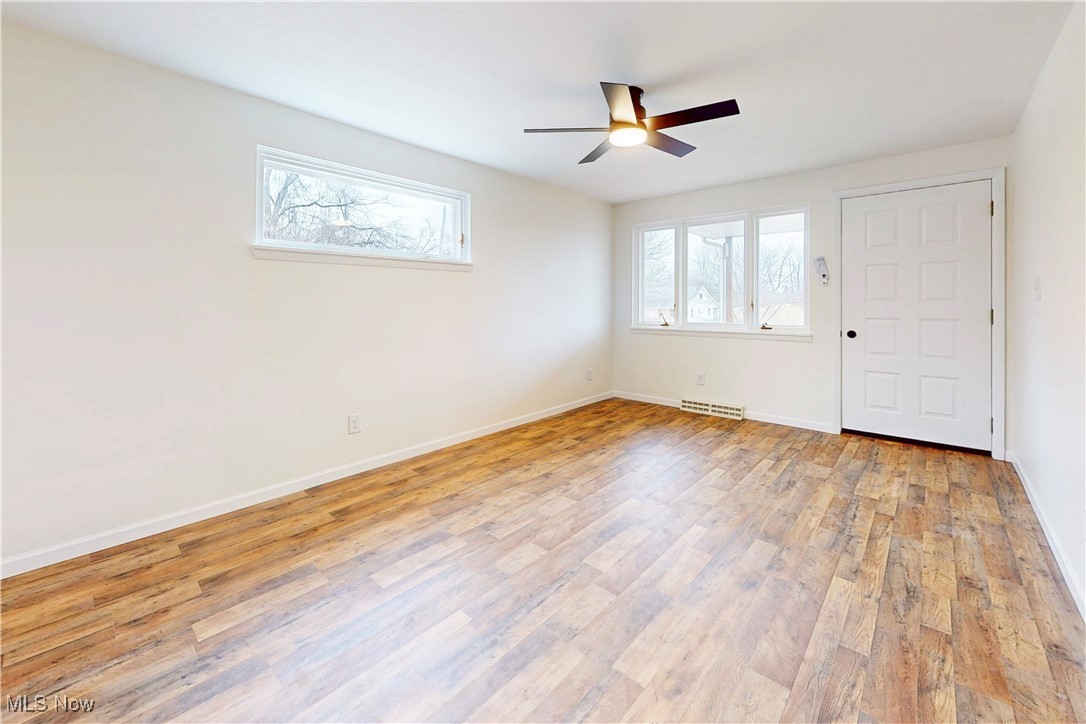 Spare room featuring light wood-type flooring, plenty of natural light, visible vents, and baseboards