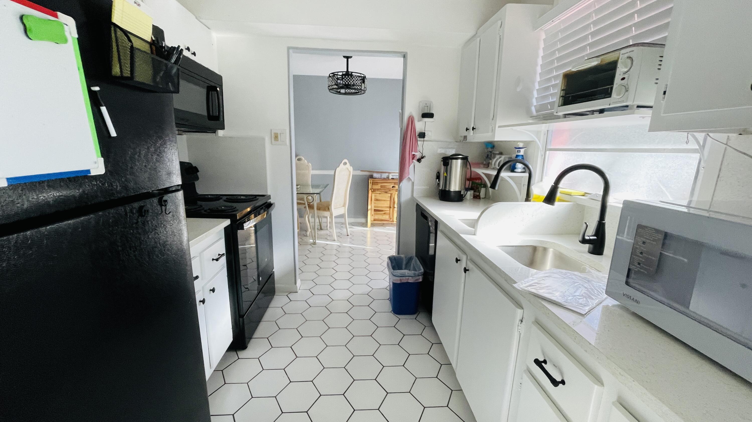 11 Golfs Edge, Unit E West Palm Beach, FL 33417 - Photo 5 of 14 a kitchen with stainless steel appliances granite countertop a refrigerator a stove top oven a sink and dishwasher