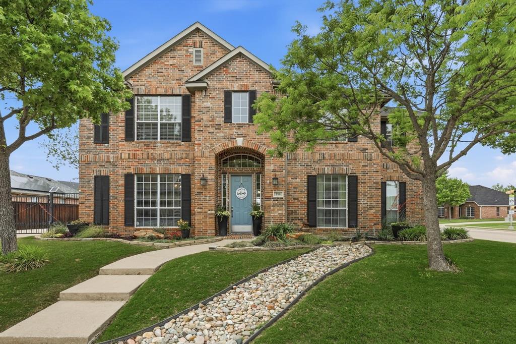 The property features a brick exterior with black window shutters and a light blue front door