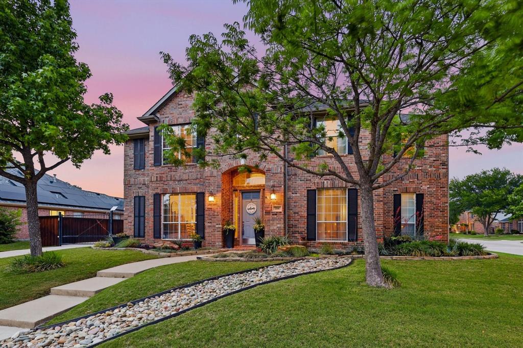 216 Durango Drive Trophy Club, TX 76262 - Photo 2 of 40 Brick exterior property with multiple windows featuring dark shutters, a well-maintained lawn, and mature trees in the front yard