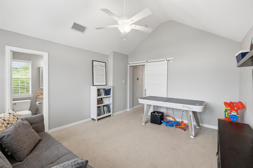 216 Durango Drive Trophy Club, TX 76262 - Photo 24 of 40 Well-lit room featuring a vaulted ceiling with a ceiling fan, carpeted flooring, and a white sliding barn door