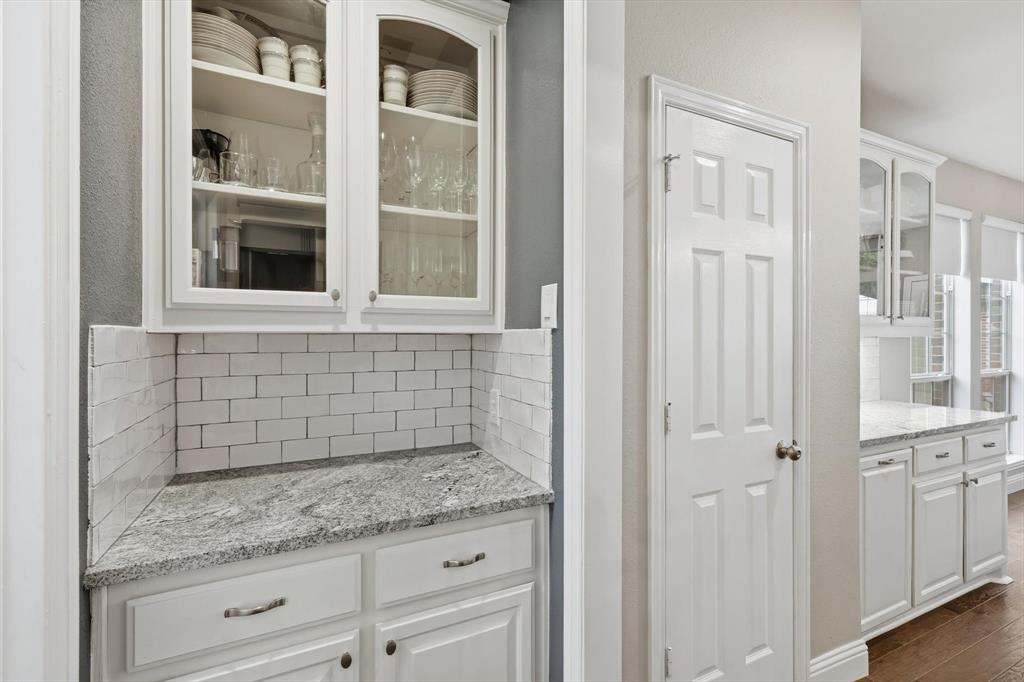 216 Durango Drive Trophy Club, TX 76262 - Photo 8 of 40 This property features white cabinetry with glass display fronts, a subway tile backsplash, and light-colored countertops