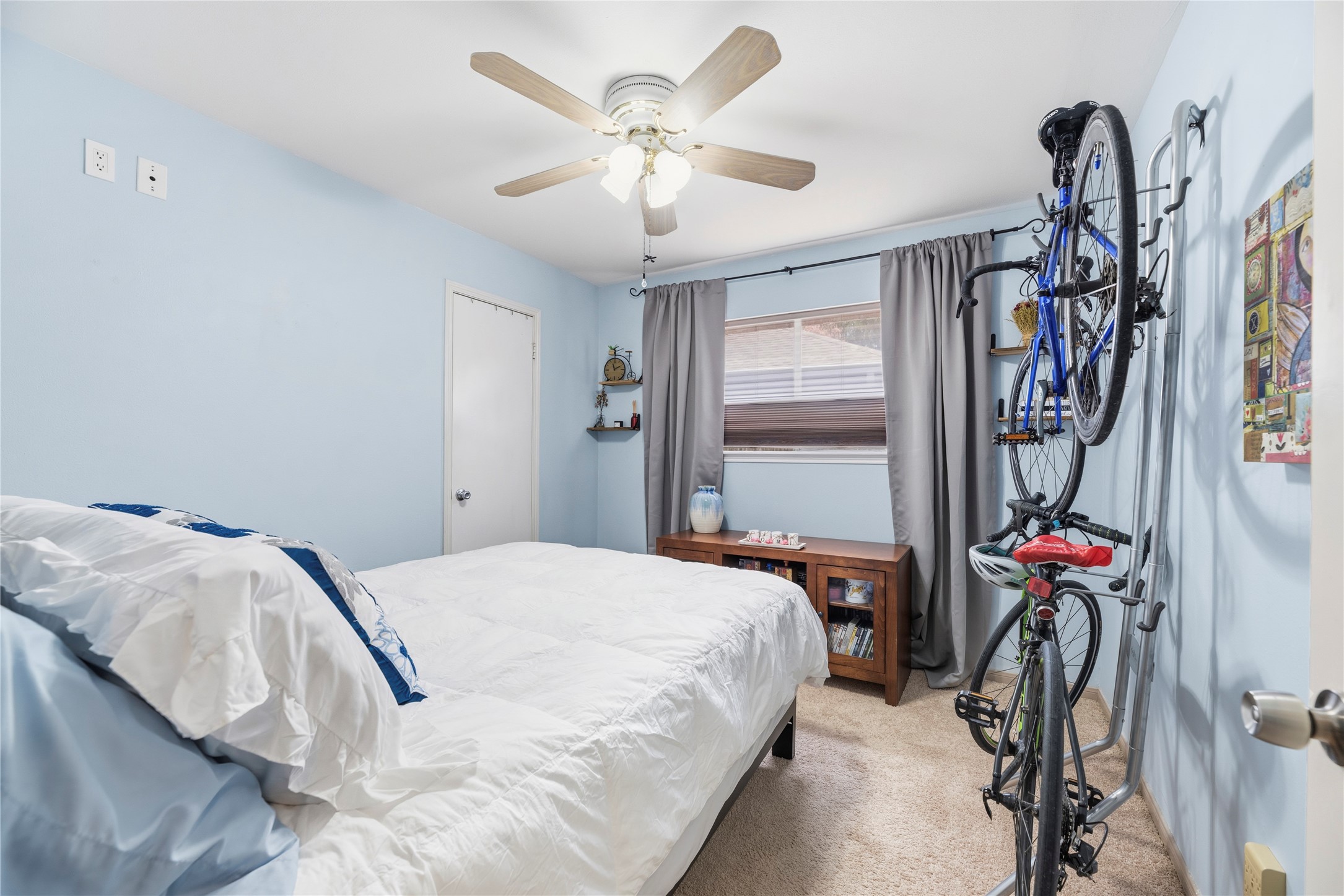 14203 Wickersham Lane Houston, TX 77077 - Photo 17 of 25 Comfortably sized secondary bedroom featuring soft wall tones, plush neutral carpeting, a large window providing natural light, a built-in closet, and a ceiling fan and cell shade.