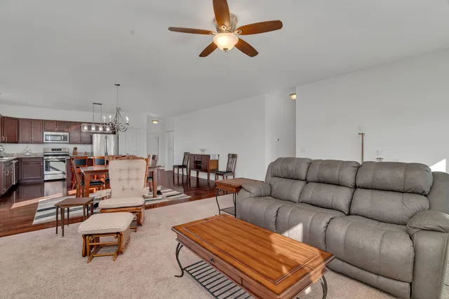 a living room with furniture kitchen view and a chandelier