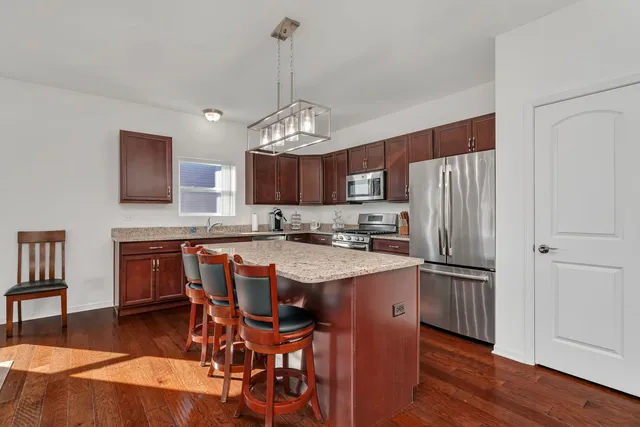 a kitchen with stainless steel appliances granite countertop a table chairs refrigerator and sink