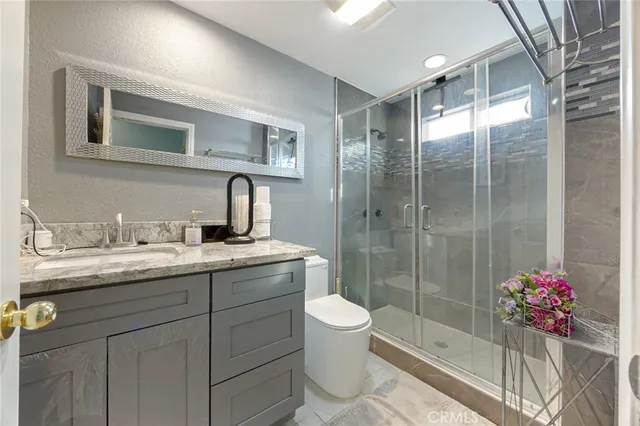 a bathroom with a shower sink vanity mirror and toilet