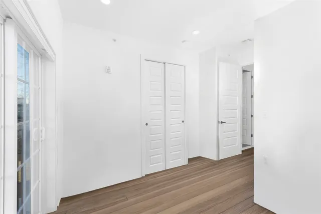 a view of an empty room with wooden floor and closet