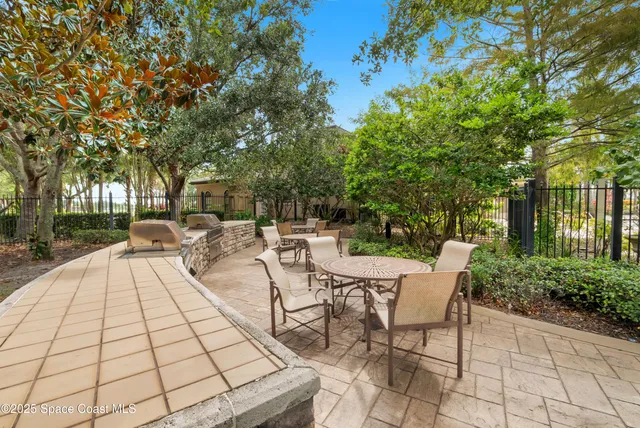 a view of a patio with table and chairs and potted plants with large trees