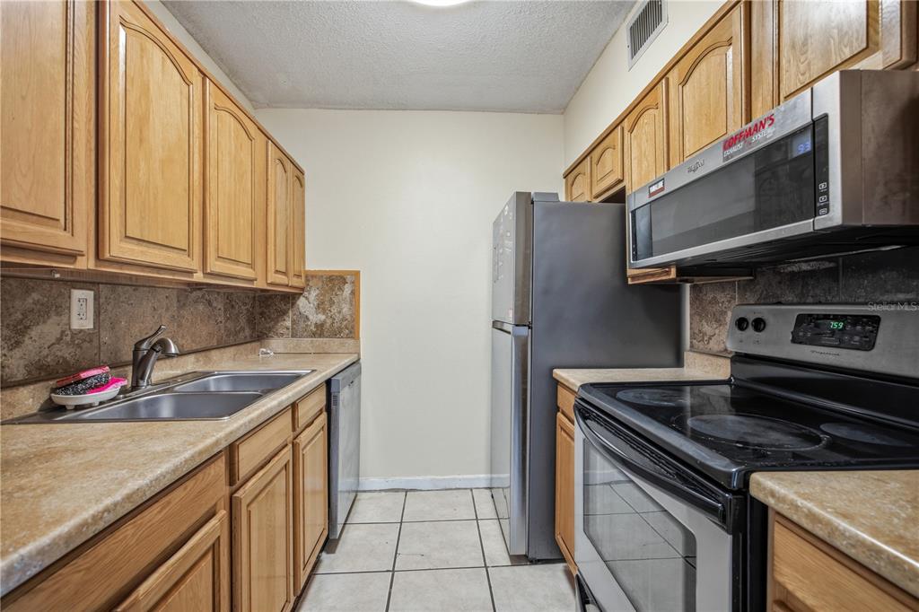 6519 West Newberry Road, Unit 109 Gainesville, FL 32605 - Photo 9 of 21 a kitchen with stainless steel appliances granite countertop a stove and a refrigerator