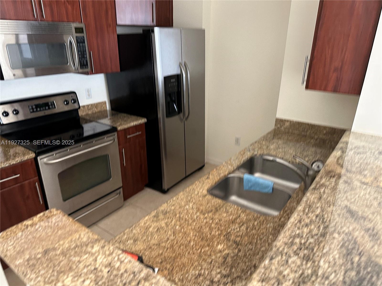 2401 Northeast 65th Street, Unit 606 Fort Lauderdale, FL 33308 - Photo 9 of 19 a kitchen with granite countertop a sink stove and refrigerator