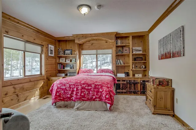 a bedroom with a bed a bookshelf and a large window