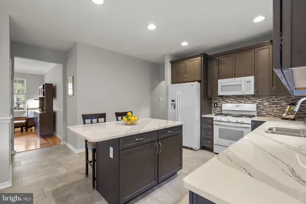 a kitchen with stainless steel appliances kitchen island granite countertop a table chairs sink and window
