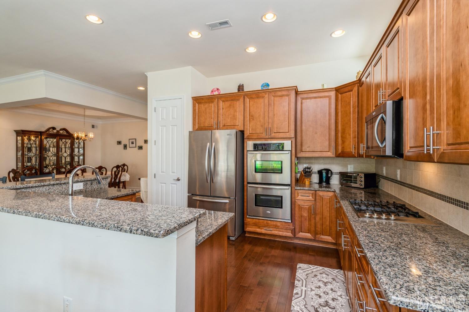 114 Riviera Drive Monroe Township, NJ 08831 - Photo 7 of 40 a kitchen with stainless steel appliances granite countertop a refrigerator a stove and a sink with wooden floor