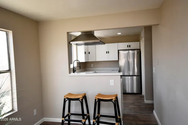 a kitchen with stainless steel appliances a refrigerator a stove a sink and a dining table with wooden floor